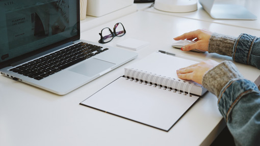 female sitting at desk with planner and laptop